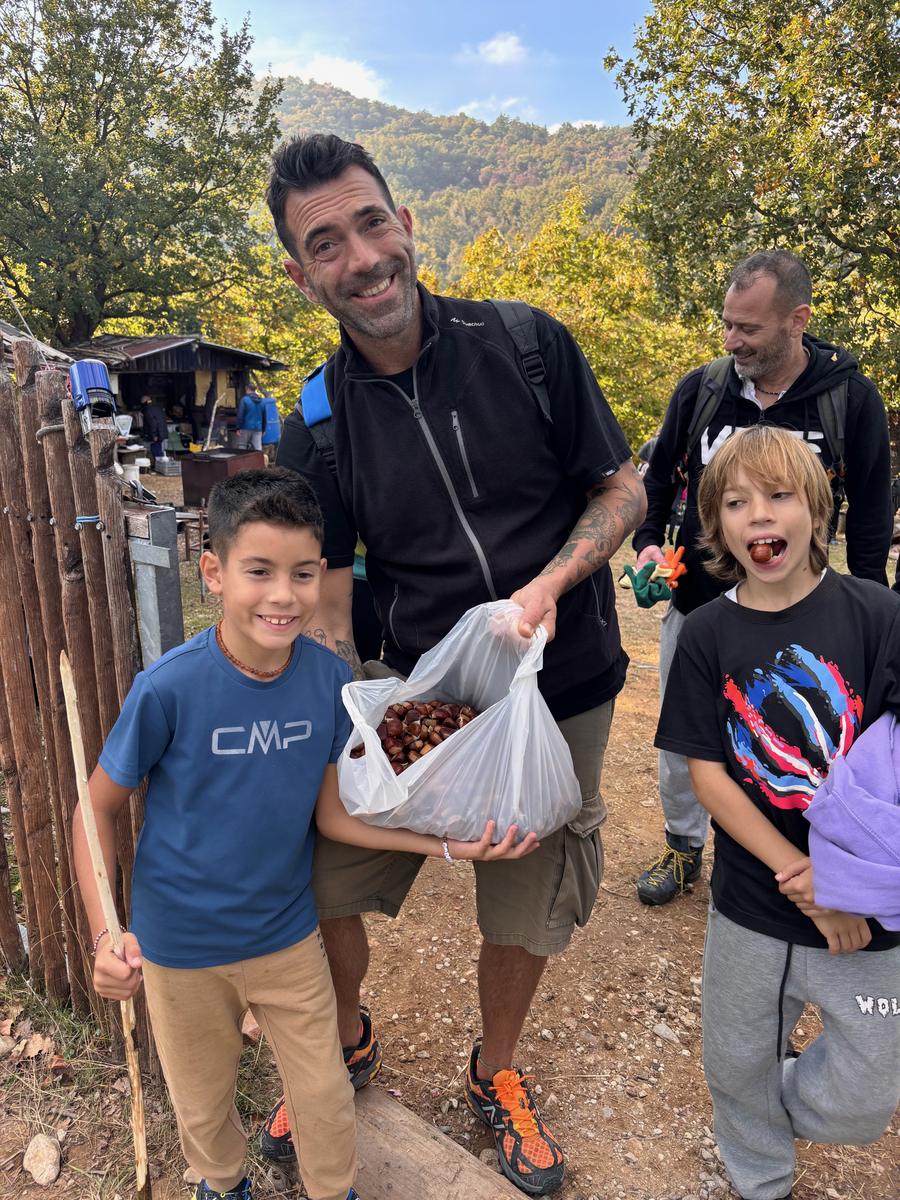 Un papà con i bambini e le castagne raccolte